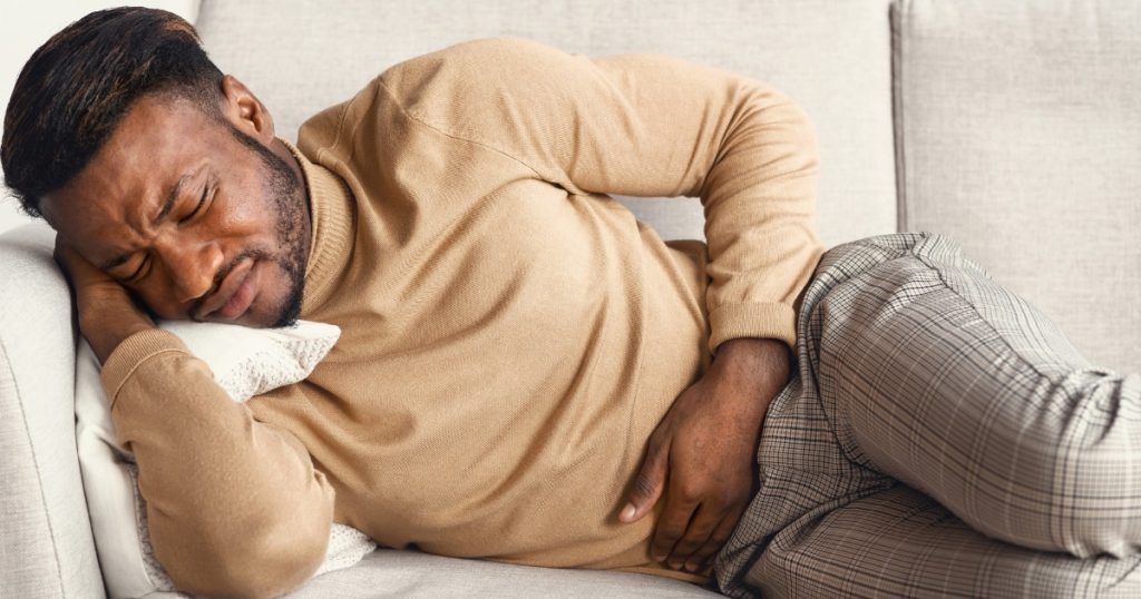 Man Touching Aching Stomach Lying On Couch